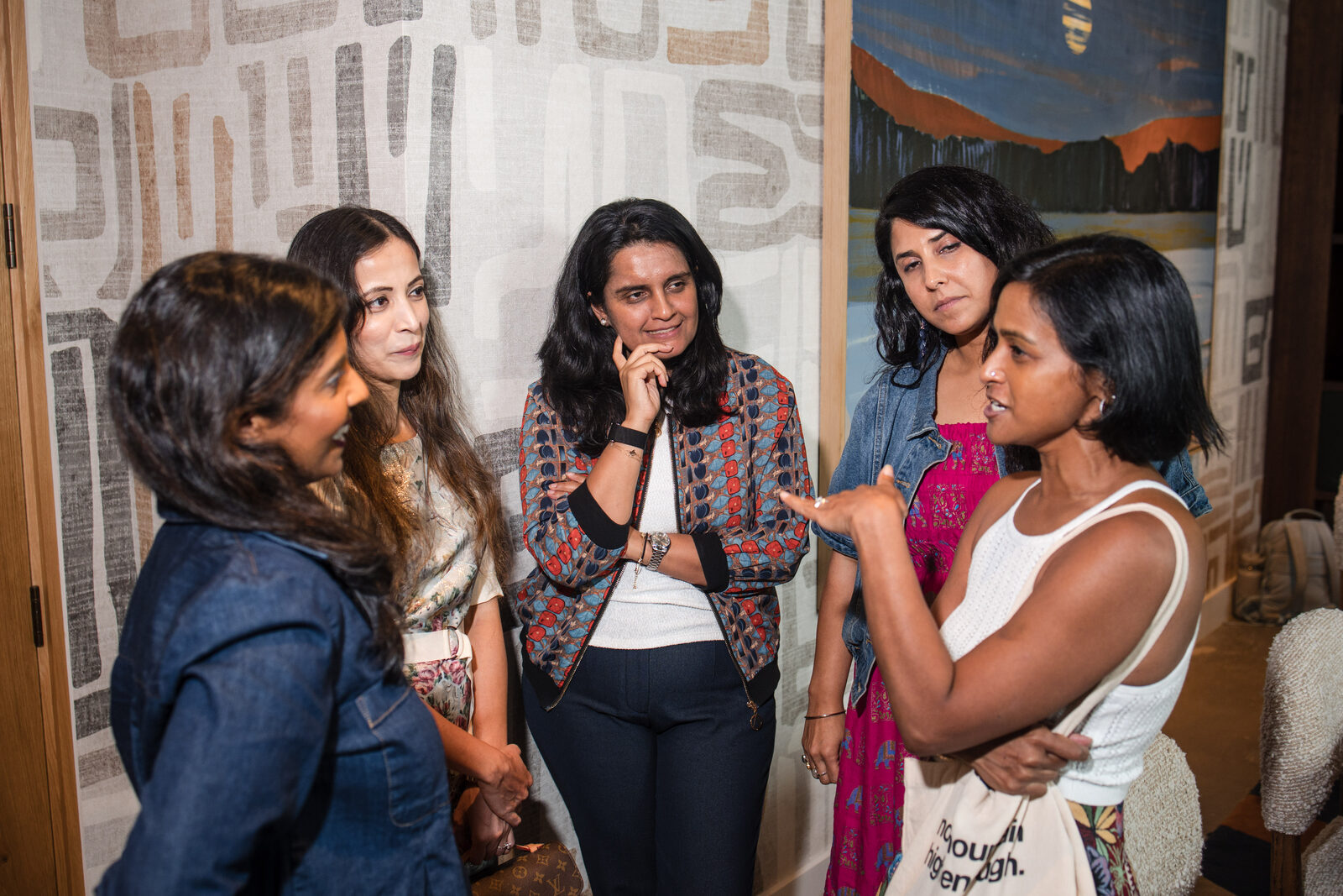 Five South Asian women in candid pre-event conversation at Chai & Chaat Austin