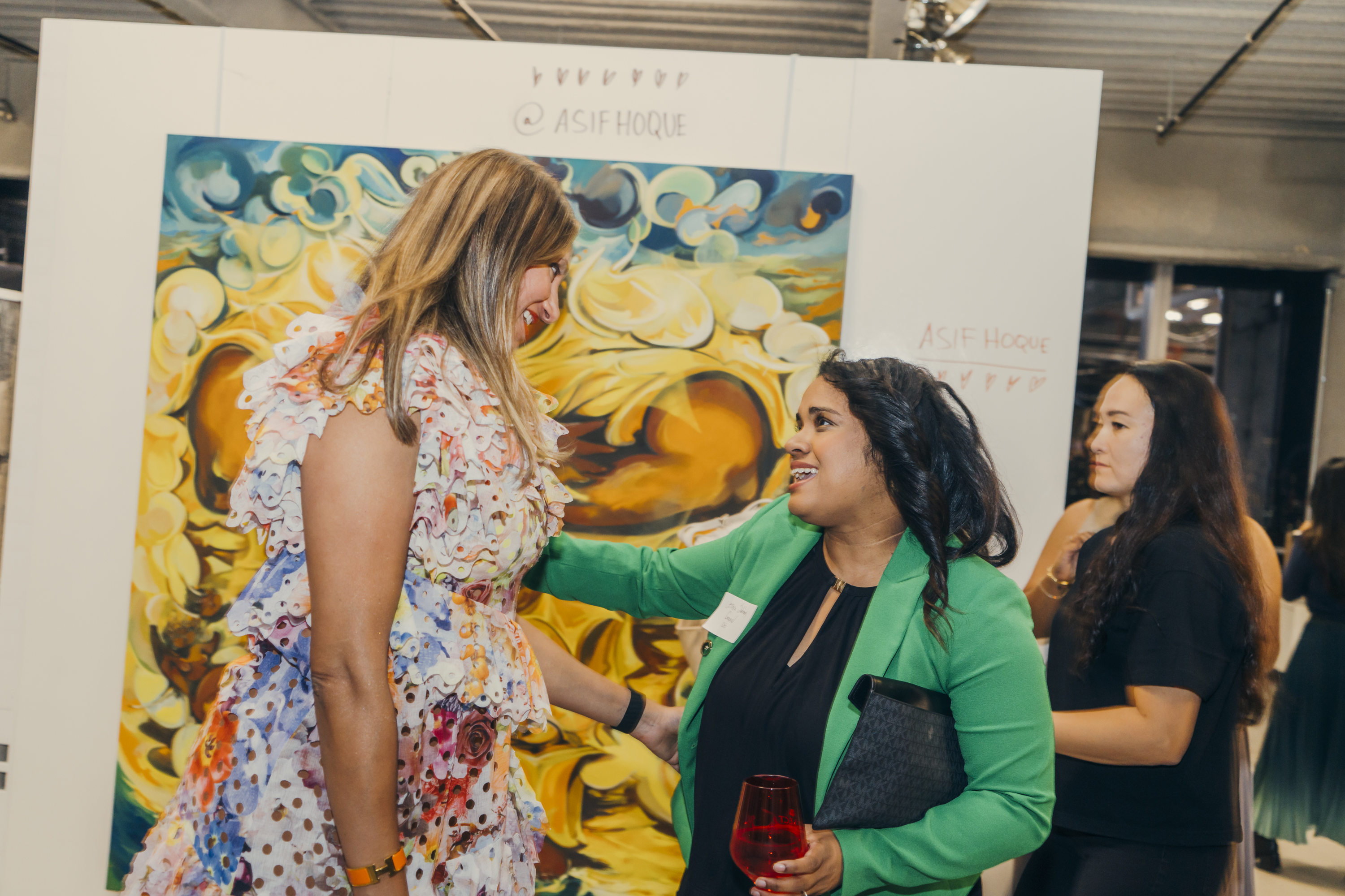 Jessica Sobhraj of CoSynd at the Brown Girl Angels SickKids fundraiser, in conversation in front of an Asif Hoque painting.
